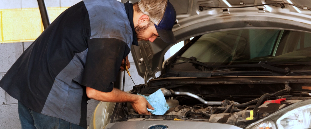 A mechanic checking an oil dipstick in a car