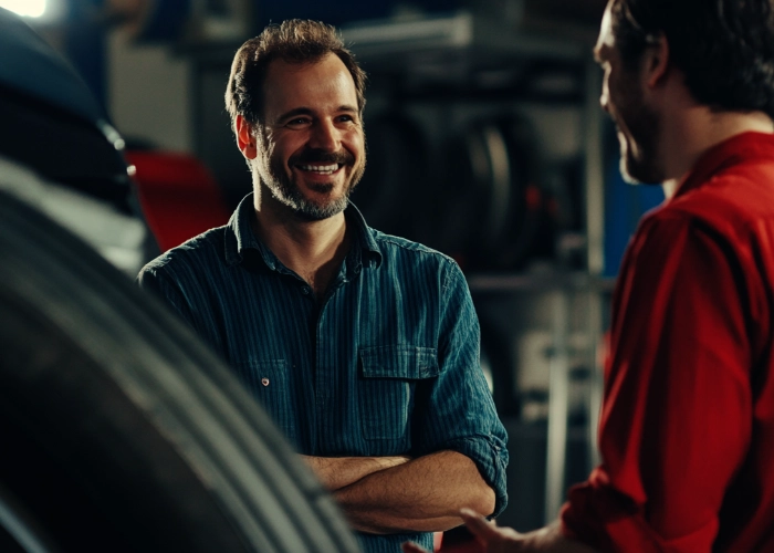 an employee happily helping out a customer next to a stack of tires